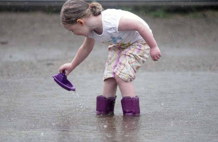 Emily Nichols, 4, launches a plastic boat Wednesday while tiptoeing through a puddle outside her Gardiner home.