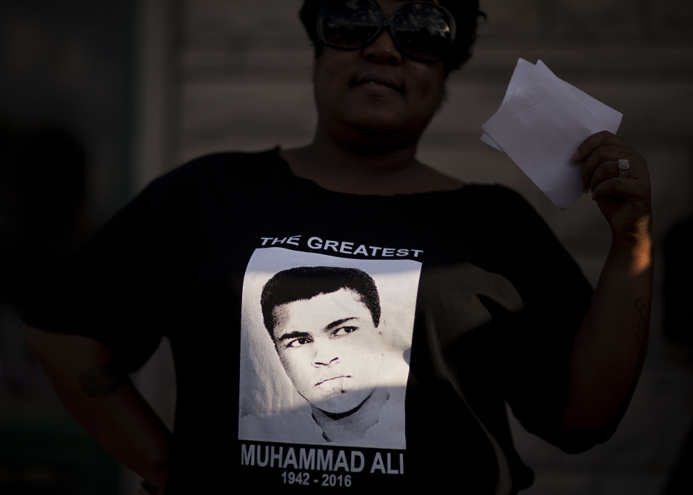 A ray of sunlight shines on a Muhammad Ali shirt worn by Nicole Morris-Cowherd as she attends a community memorial service to Ali outside his childhood home Monday in Louisville, Ky.