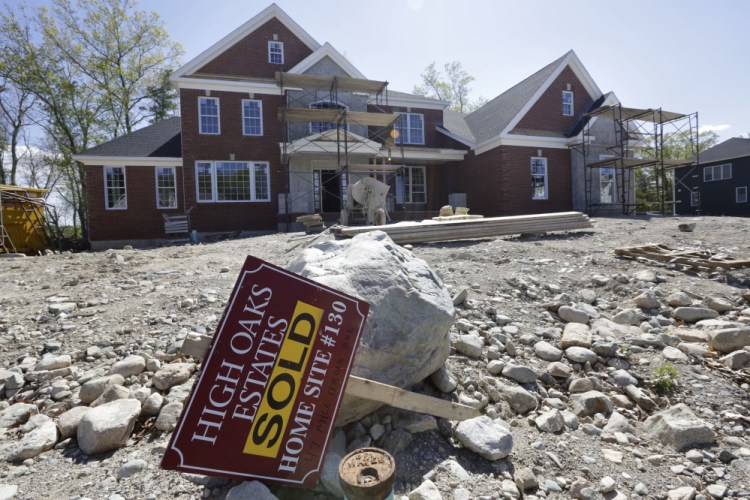 A "Sold" sign rests in front of a house under construction, in Walpole, Mass. The Commerce Department reports on sales of new homes dropped in May.