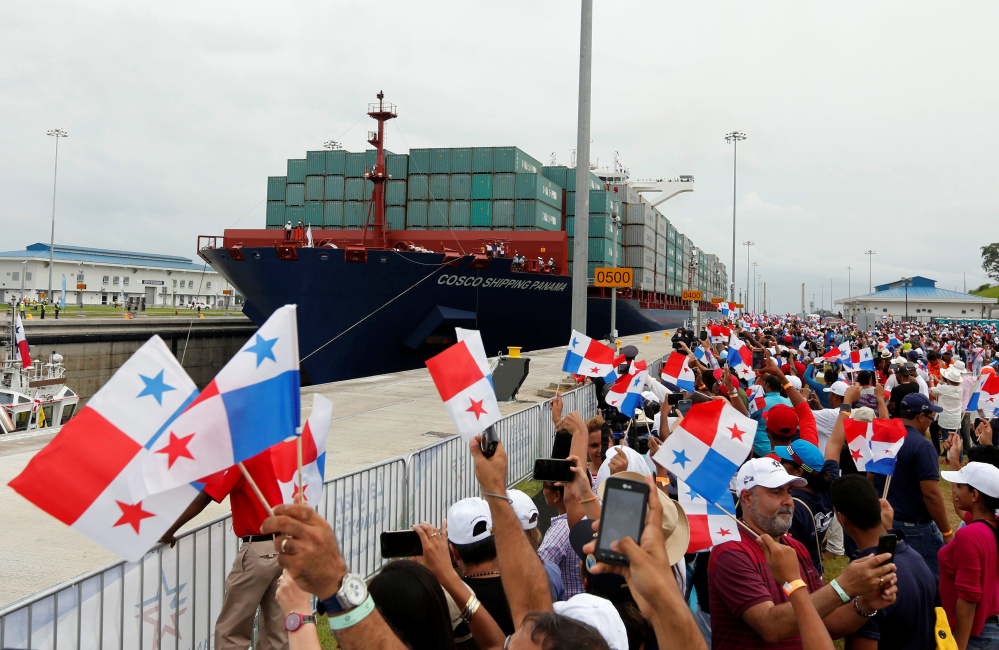 People wave Panamanian flags as a massive Chinese COSCO container vessel navigates through the Agua Clara locks during the first ceremonial pass through the Panama Canal on Sunday.