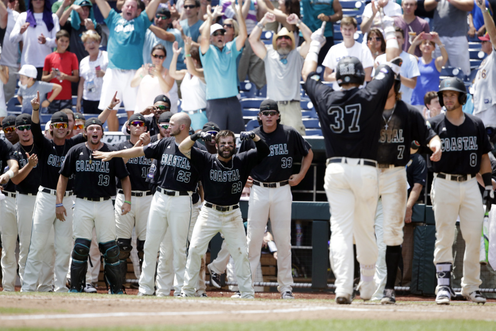 Coastal Carolina's G.K. Young, 37, and the dugout celebrate as Young touches home plate after hitting a two-run home run against Arizona in the sixth inning in Game 3 of the College World Series in Omaha, Neb. on Thursday afternoon.
