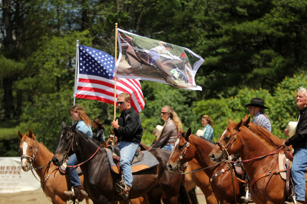 Hardy Cummings holds a flag with a photo of his late daughter during the singing of the National Anthem before the start of the Halee Lyn Cummings Memorial Barrel Race at the Silver Spur Riding Club in Sidney on Sunday. Halee Cummings, 18, of Sidney, died in an ATV accident last year.