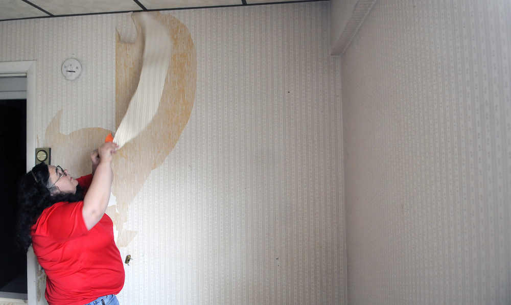 Volunteer Karen St. Peter strips wallpaper from a room at 8 Summer St. in Augusta in May while work was underway to transition the home into a place for homeless female veterans.