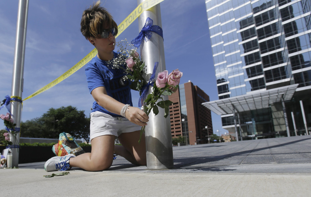 Noelle Hendrix places flowers near the scene of a shooting in downtown Dallas, Friday, July 8, 2016. Snipers opened fire on police officers in the heart of Dallas during protests over two recent fatal police shootings of black men. (AP Photo/LM Otero)