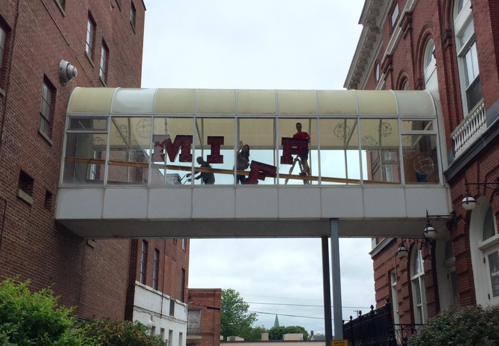 People hang large letters spelling "MIFF" Friday afternoon in the skywalk connecting The Center and the Waterville Opera House/City Hall in preparation for opening night of the Maine International Film Festival.