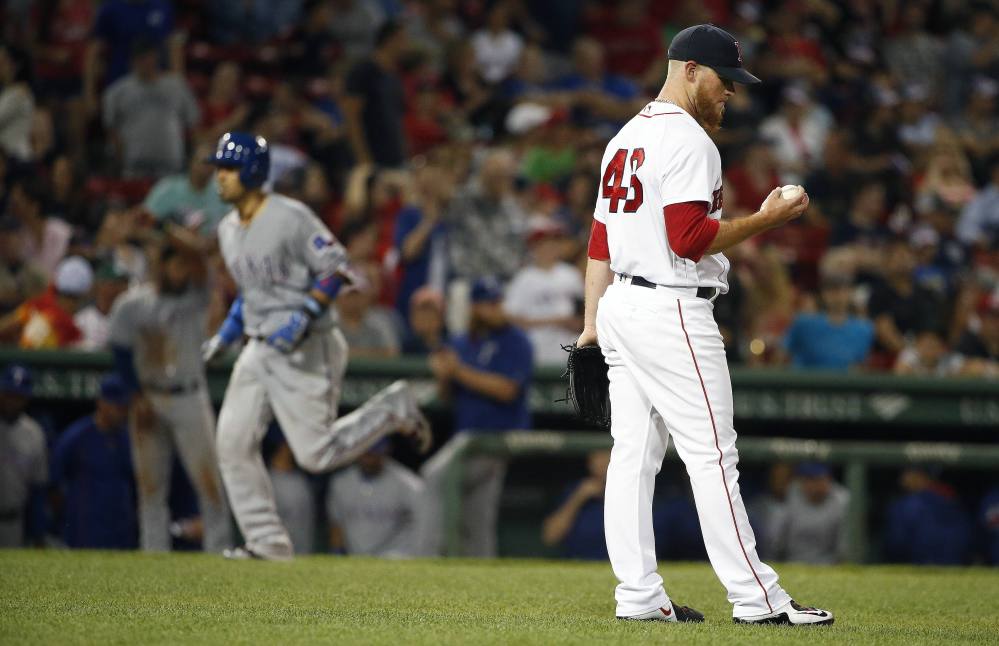Boston Red Sox' closer Craig Kimbrel examines a new ball after giving up a three-run home run to Texas' Robinson Chirinos, left, during the ninth inning Tuesday at Fenway Park.