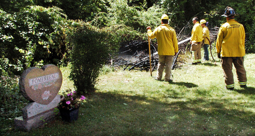 Waterville firefighters extinguish a suspicious fire Thursday in some brush beside grave sites at the St. Francis Catholic Cemetery in Waterville.