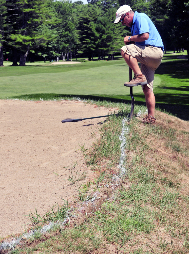 John Roberts cuts an edge on a bunker at the Augusta Country Club on Wednesday in Manchester.