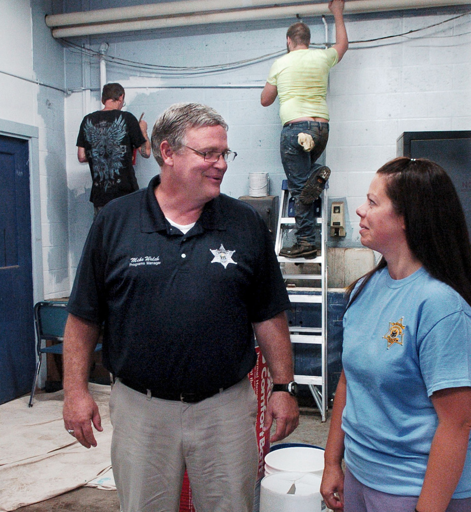 Somerset County Jail Programs Manager Mike Welch speaks with Community Corrections Program Manager Teresa Brown as participants in a community service program paint walls at Madison Junior High School on July 17.