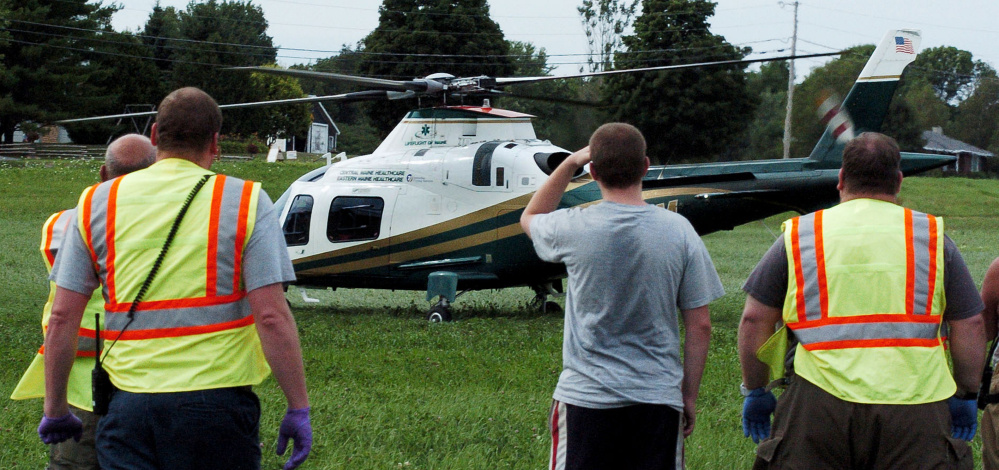 Fairfield first responders watch as a Lifeflight helicopter lands in a field near a car accident scene Monday on Center Road. Jeff Neill, of Fairfield, was taken to Central Maine Medical Center in Lewiston with serious injuries.