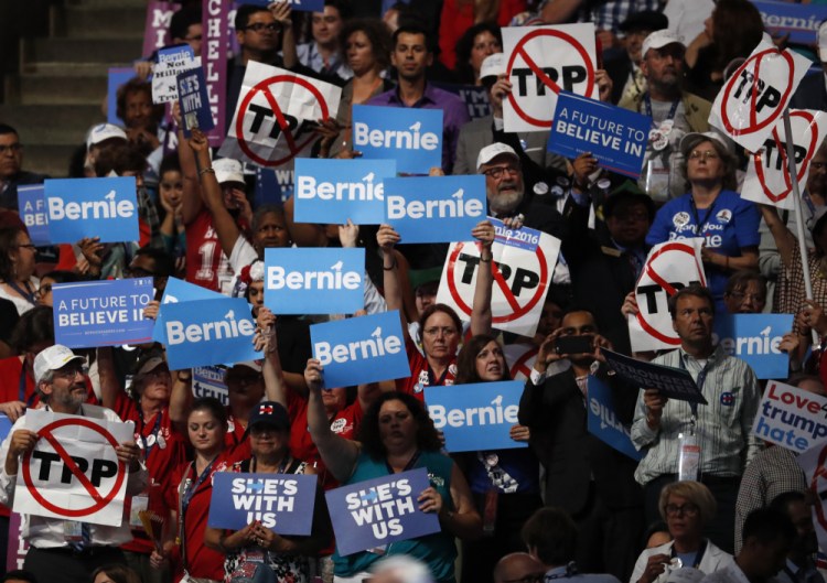Bernie Sanders supporters hold signs, including those critical of the Trans-Pacific Partnership, or TPP, during the first day of the Democratic National Convention in Philadelphia on Monday.