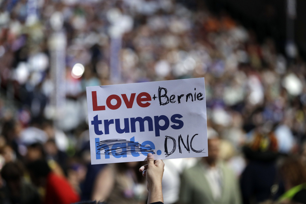 A delegate holds up a sign during the first day of the Democratic National Convention in Philadelphia on Monday. Several delegates supporting Bernie Sanders on Monday took campaign signs that read "Love trumps hate" and modified them to instead read "Love + Bernie trumps DNC" or "Love Bernie or trump wins."