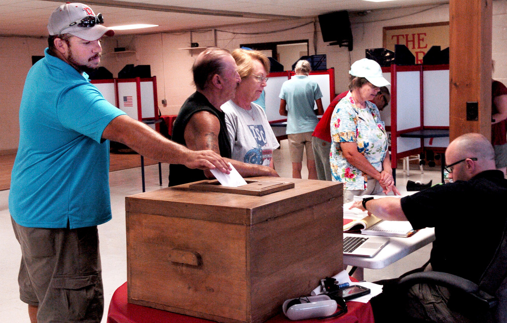 Mark Simpson casts his vote Thursday on the Regional School Unit 9 budget as other voters receive ballots at the Farmington Community Center in Farmington. The 10 towns in the district voted for the second time this summer on the budget, which passed.