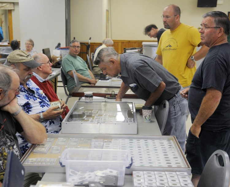 People look at antique currency on display Sunday at the Capital City Coin Show, held at the Elks Lodge in Augusta.