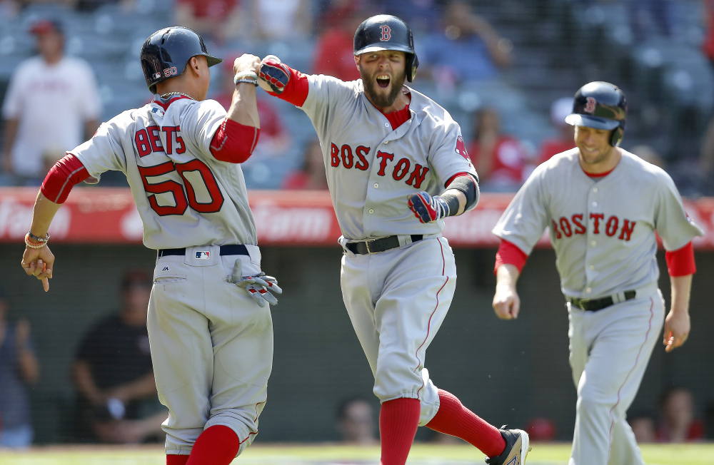 Boston's Dustin Pedroia, center, celebrates with Mookie Betts, left, after hitting a three-run home run to put them ahead of the Los Angeles Angels during the ninth inning Sunday in Anaheim, California. The Red Sox held on to win 5-3.