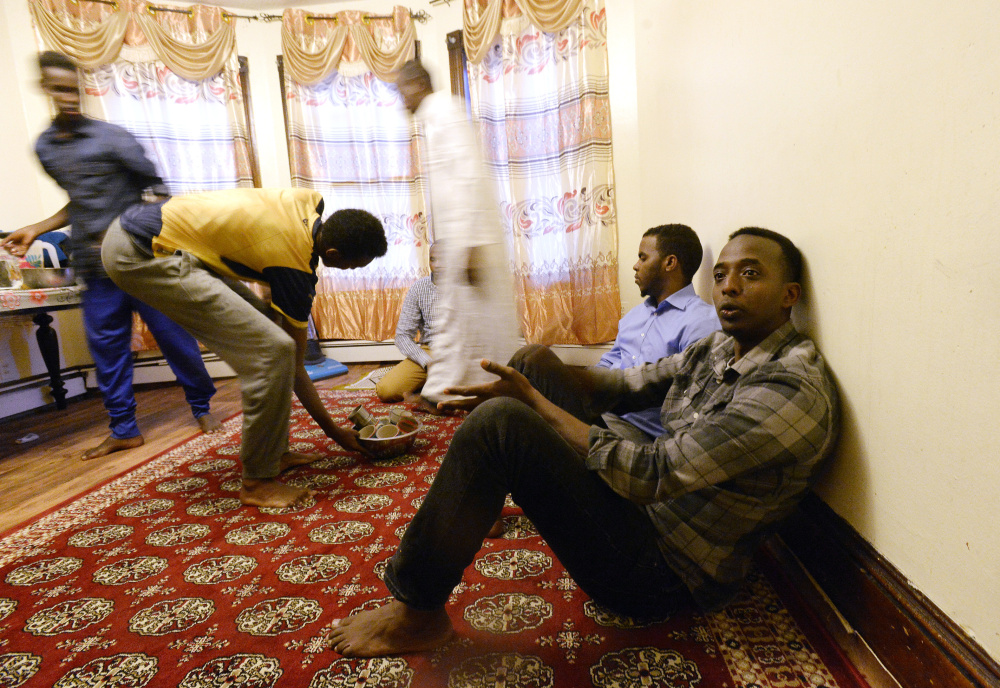 Abdi Nor Iftin sits with fellow Maine Somalis as food is brought out for an iftar, the traditional sunset meal Muslims eat to break the fast of Ramadan, last Tuesday evening in Lewiston.