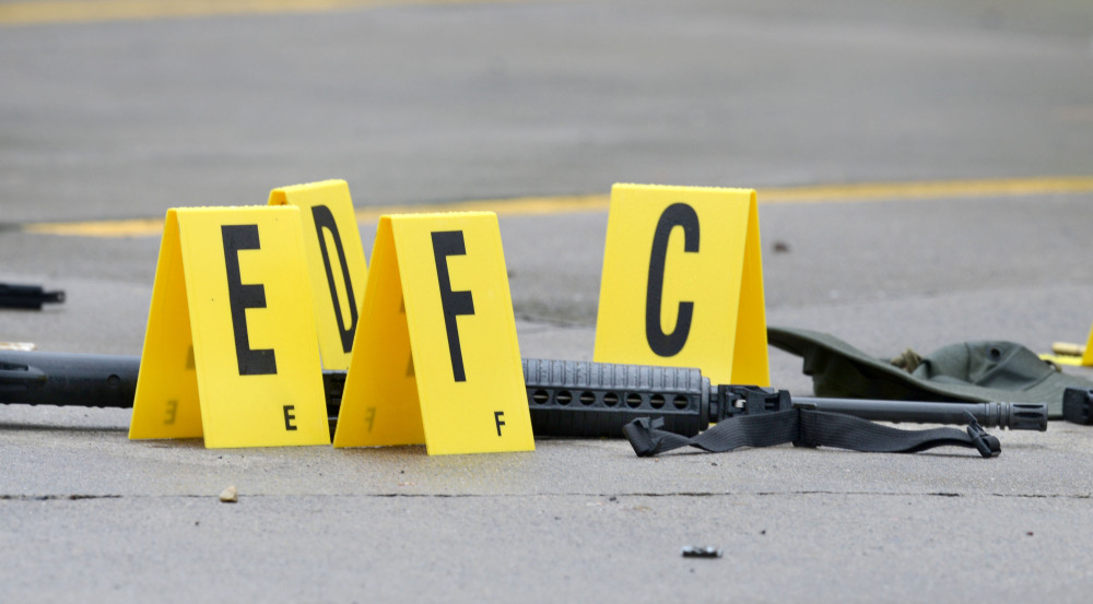 A weapon lies on the ground next to evidence markers in Bristol, Tenn., on Thursday. Police say a black Army veteran shot at passing cars and police on a Tennessee highway, and later told investigators that he was troubled by police violence against African-Americans.