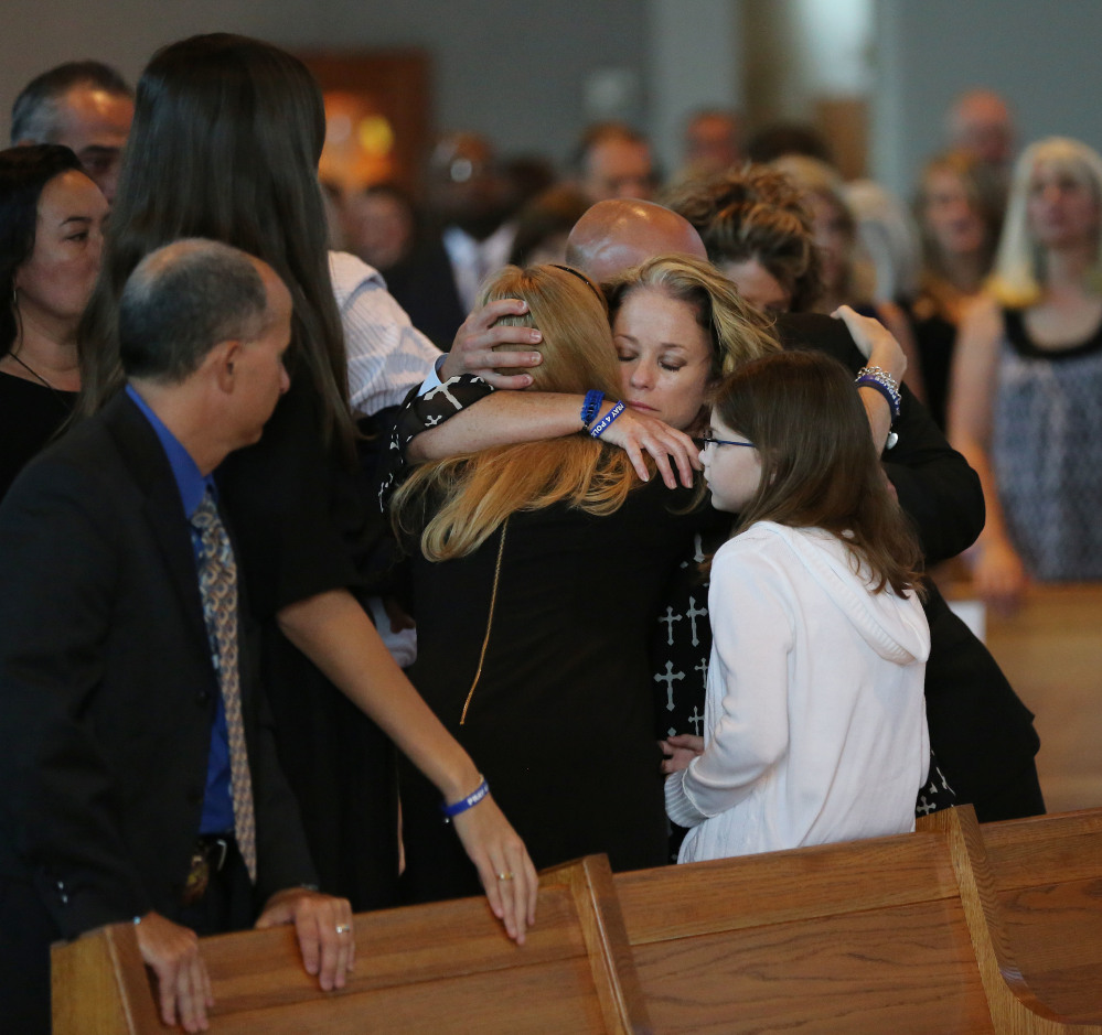 Dallas Sr. Cpl. Marcie St. John, second to right, hugs Heidi Smith, the wife of Dallas police Sgt. Michael Smith, during the funeral for Smith at the Mary Immaculate Catholic Church in Farmers Branch, Texas, on Wednesday. Smith and four other officers were killed during an attack following a peaceful Black Lives Matter protest on July 7.