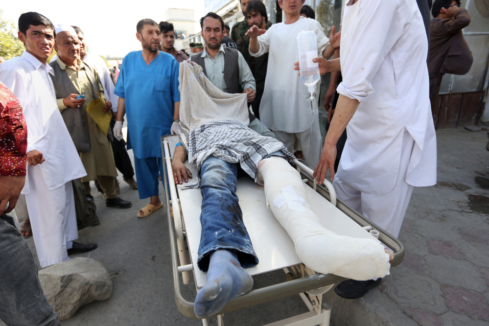 Afghans help an injured man after an explosion struck a protest in Kabul on Saturday.