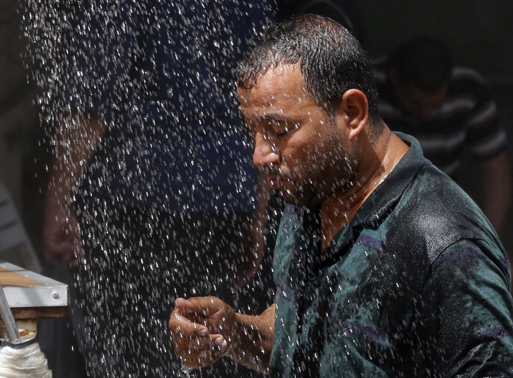 An Iraqi man cools off under an open-air shower in Baghdad on Saturday. Iraqis are enduring the year's hottest temperatures in the southern part of the country, compounded by electricity outages.