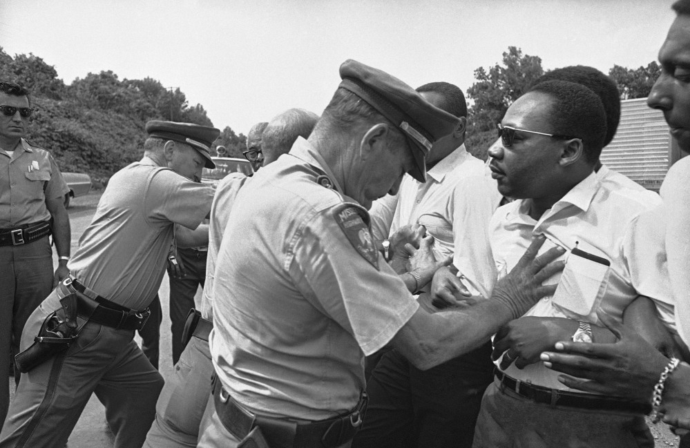 FILE - In this June 7, 1966 file photo, Mississippi Highway Patrolmen shove the Rev. Martin Luther King and members of his marching group off the traffic lane of Highway 51 south of Hernando, Miss. King, Student Non-Violent Coordinating Committee leader Stokely Carmichael (head visible at upper right) and other civil rights leaders had taken up the march begun by James Meredith. (AP Photo)