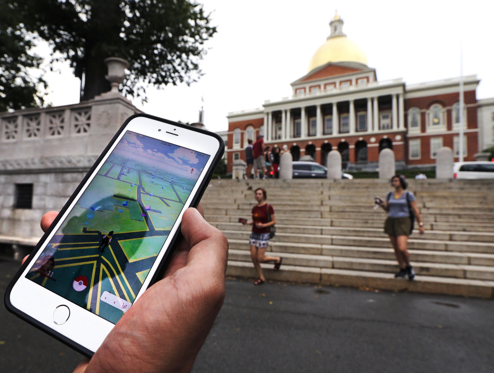 A "Pokemon Go" player looks at his mobile phone while walking through Boston Common outside the Massachusetts Statehouse. The founder of the volunteer-based historical markers website that licensed its data to game-maker Niantic Labs five years ago said he hopes enough people take their eyes off the Pokemon they're trying to catch to read the history on the markers.
