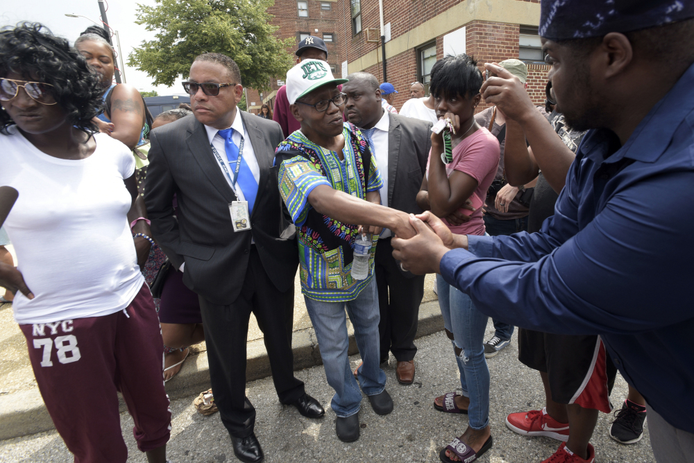 Elder C.D. Witherspoon, right, shakes the hand of Freddie Gray's father Richard Shipley, center, as Gray's mother Gloria Darden, left, and twin sister Fredericka Gray, second from right, stand nearby after a news conference held by Baltimore State's Attorney Marilyn Mosby Wednesday.