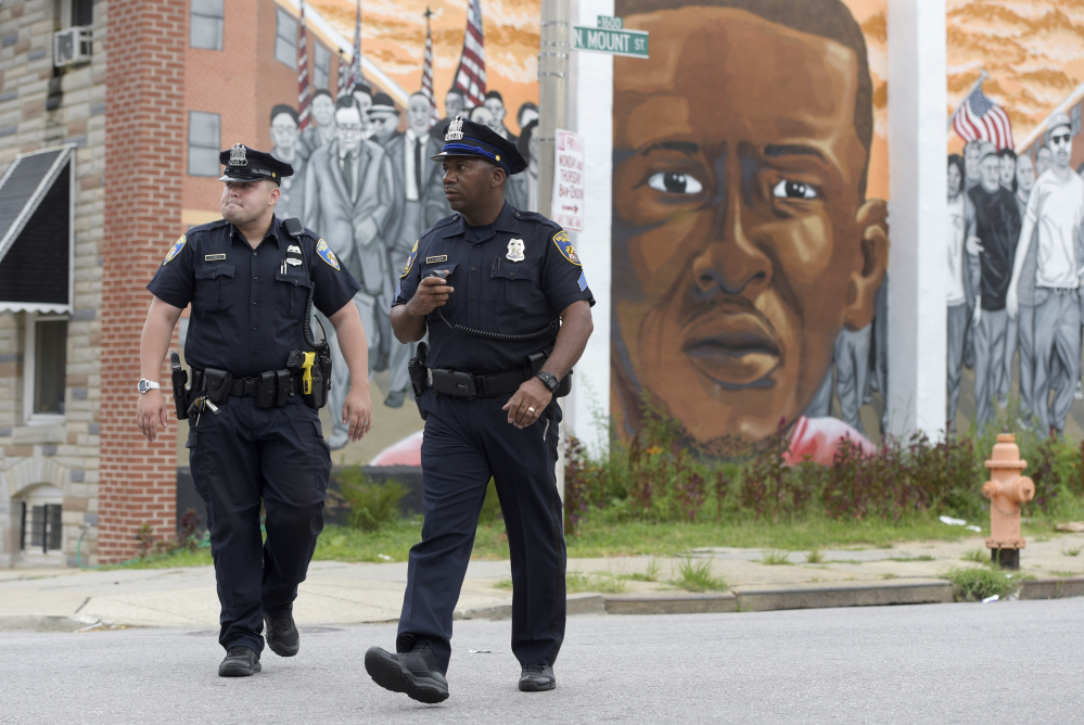 Baltimore police walk near a mural depicting Freddie Gray after prosecutors dropped remaining charges against the three Baltimore police officers who were still awaiting trial in Gray' death. The decision by prosecutors comes after a judge had already acquitted three of the six officers charged in the case.