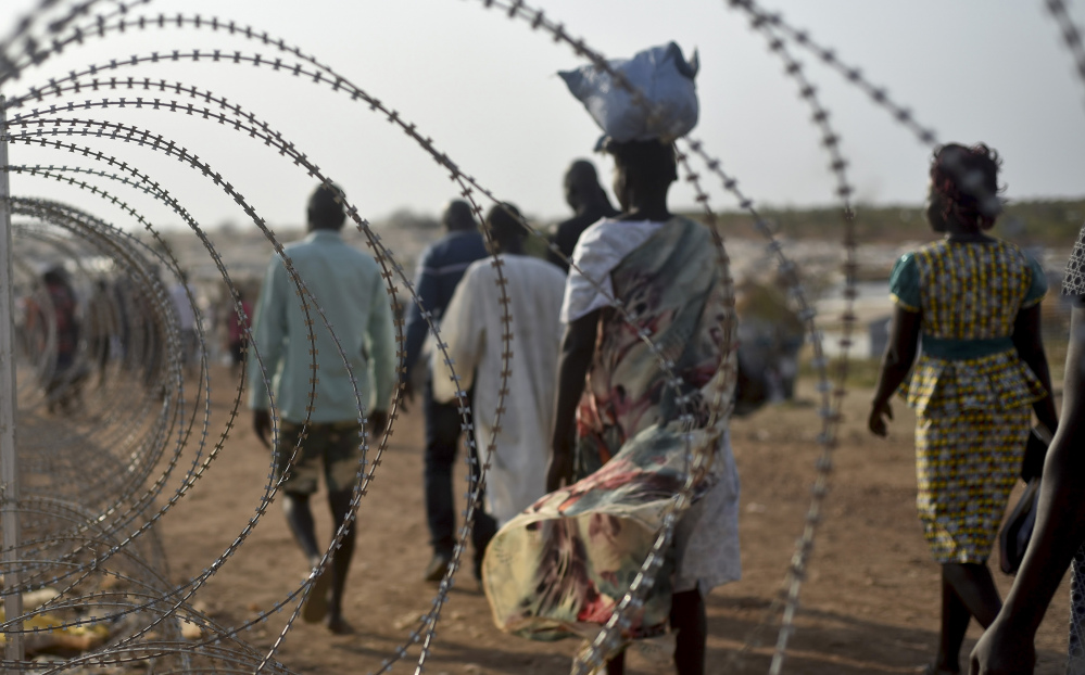 People walk next to a razor wire fence at the United Nations base in the Juba, South Sudan, last January. Ethnic Nuer women and girls were reportedly raped near here last week.