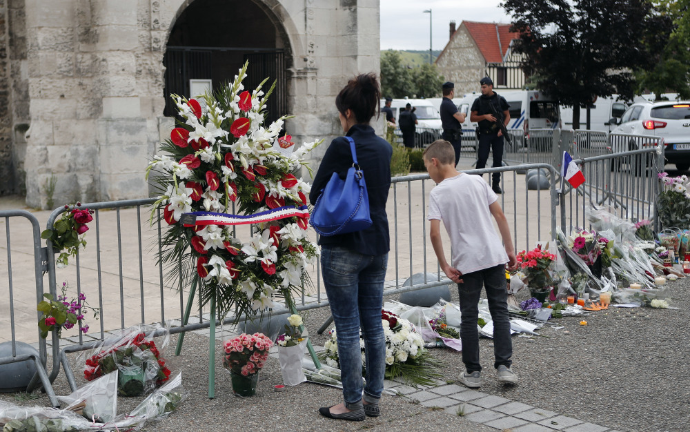 People pay respects Wednesday outside a church in the village of Saint-Etienne-du-Rouvray, in Normandy, France, where an 85-year-old priest was slain Thursday.