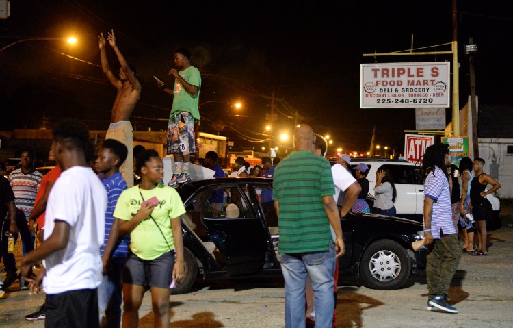 Protesters gather near the Triple S Food Mart after Alton Sterling was shot and killed by Baton Rouge police in early Tuesday morning. Officers went to the store after an anonymous caller indicated a man selling music CDs and wearing a red shirt threatened him with a gun, said Cpl. L'Jean McKneely.  Hilary Scheinuk/The Advocate via AP