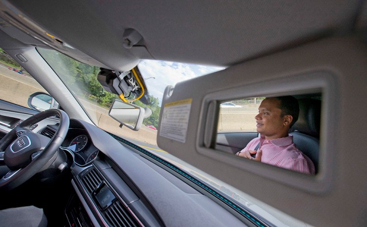 Kaushik Raghu, senior staff engineer at Audi, is reflected in the passenger-side visor mirror while demonstrating a self- driving vehicle on I-395 n Arlington, Va., Friday, July 15, 2016. Pablo Martinez Monsivais/Associated Press