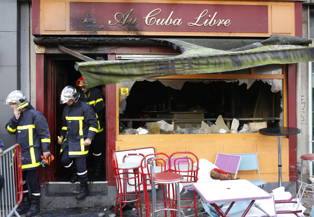 Firefighters walk out of a bar where a fire broke out in Rouen, France. A fire swept through a Friday night birthday party at the bar, killing at least 13 people and injuring six others.