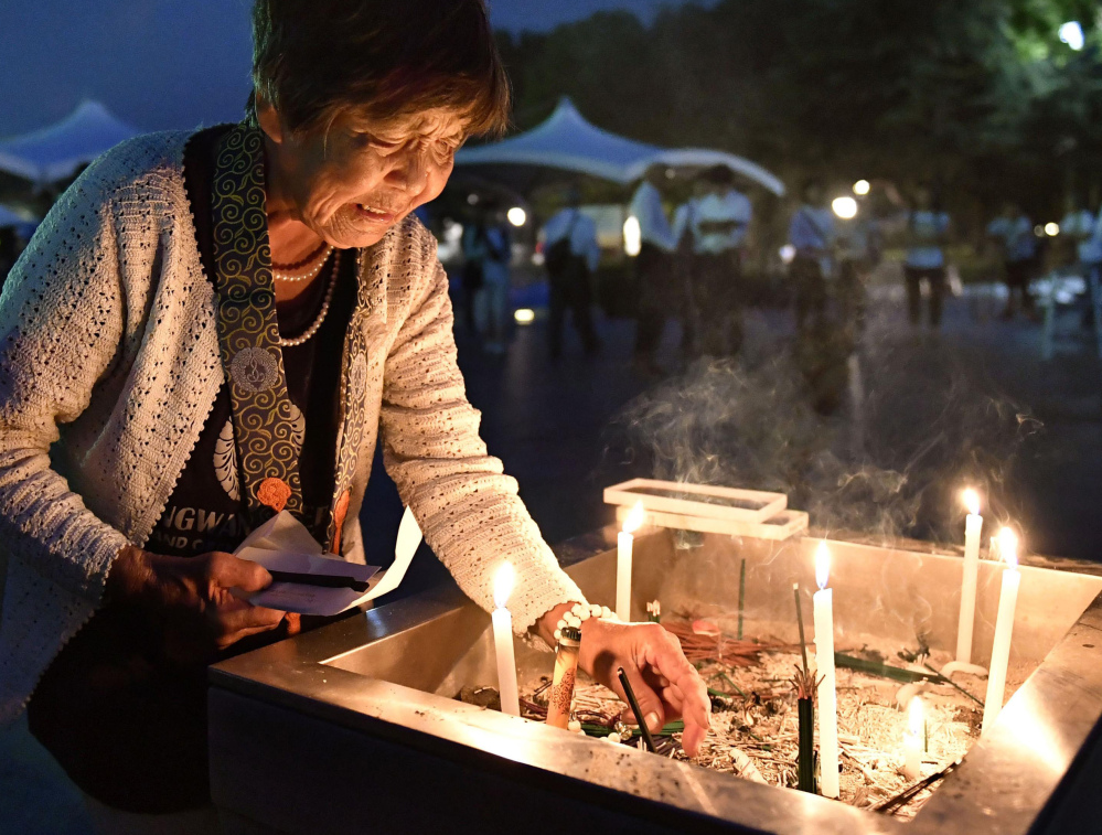 A woman lights a candle as she prays for the atomic bomb victims at the Hiroshima Peace Memorial Park.