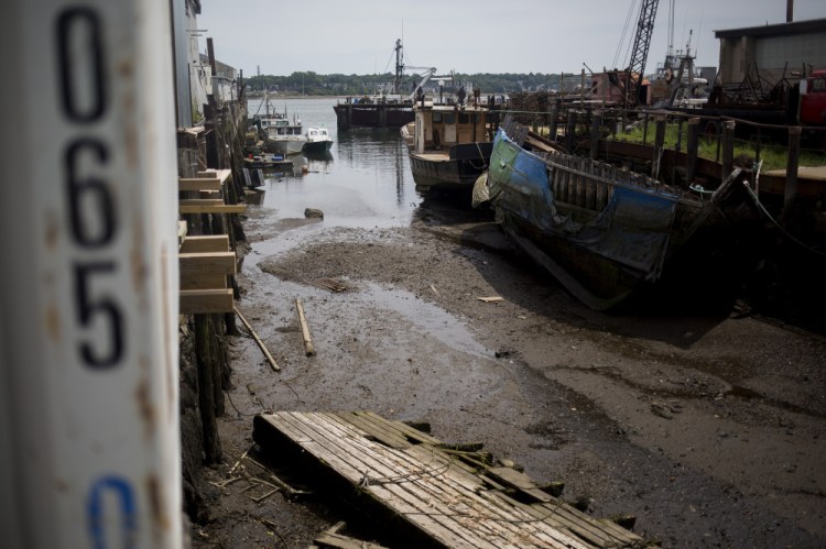 Boats lie in silt during low tide at Sturdivant's Wharf along Portland Harbor. Numerous public and private wharves have lost valuable berthing spaces as silt carried down the Fore River and from occasional sewer and stormwater runoff has built up around them.
Brianna Soukup/Staff Photographer