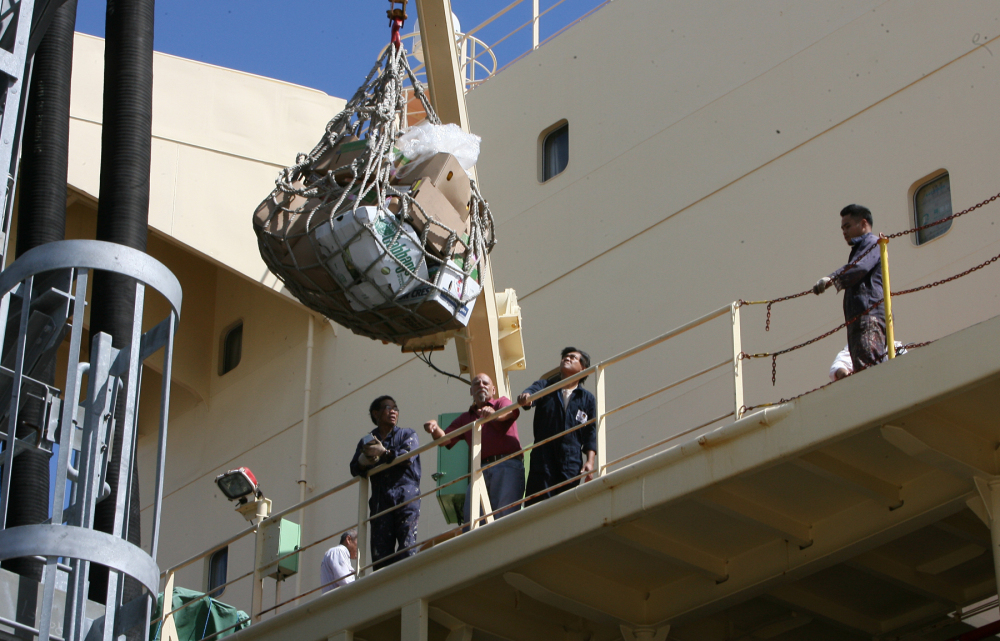 Crew members receive supplies hoisted to the Newlead Castellano on Tuesday in Savannah, Ga. The cargo vessel has been stranded near Tybee Island for nearly four months, waiting out a dispute between its Greek owner and its creditors.