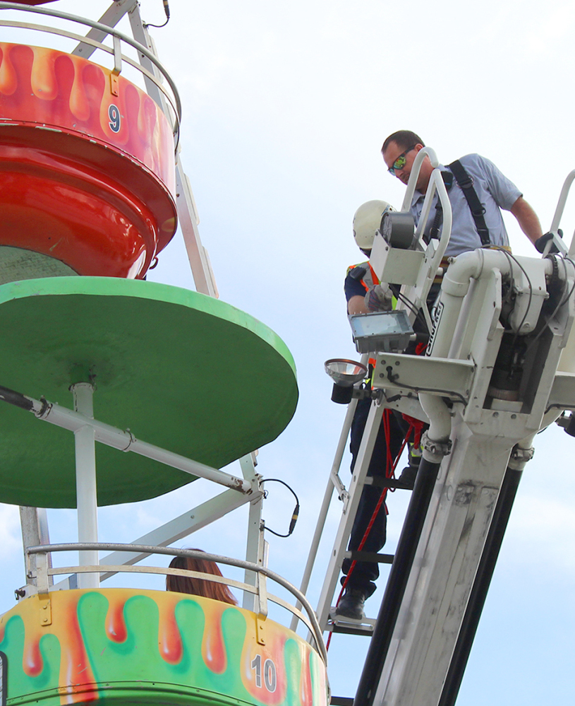 Members of the Greeneville Fire Department help people off the Ferris wheel from which three children fell on Monday during a county fair in Greeneville, Tenn.