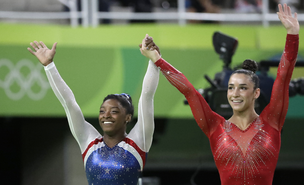Simone Biles, left, and her teammate Aly Raisman celebrate after winning the gold and silver medals, respectively, in the artistic gymnastics all-around final Thursday.