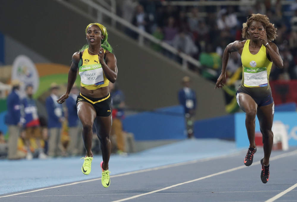 Jamaica's Shelly-Ann Fraser-Pryce, left, and Ecuador's Narcisa Landazuri run in a women's 100-meter heat Friday night. Fraser-Pryce, the only woman to beat 11 seconds, advanced in her bid to become the only woman to win the same individual track event in three straight Olympics.