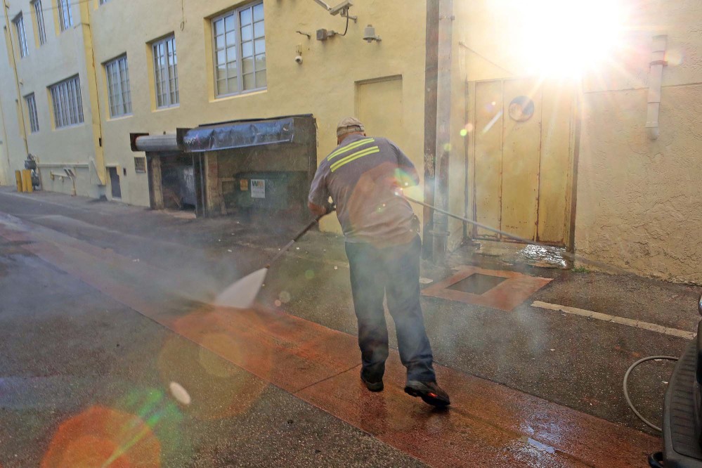 Melvin Gaitan of the Miami Beach Sanitation Department washes an alley Friday with a high pressure water machine that is set to 250 degrees Fahrenheit, which kills any bacteria or mosquito larvae that could be growing in still waters.