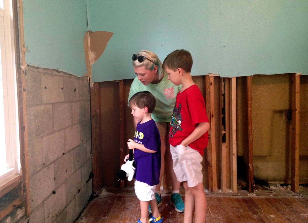 Amanda Burge, 35, looks at flood damage with her sons Aiden, right, and Hudson at their home in Denham Springs, La., Friday. "Everything is gone," she said.