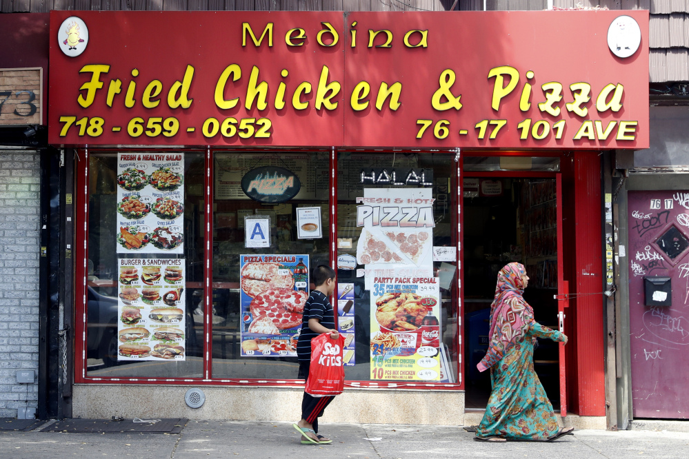 A Muslim mother and son walk past a Halal restaurant in the Ozone Park section of Queens, N.Y. 