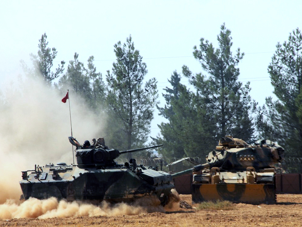 A Turkish army tank and an armored vehicle maneuver near the Syrian border in Karkamis, Turkey, on Tuesday. Hundreds of fighters backed by Turkey are preparing for an assault on a town in northern Syria held by the Islamic State group.