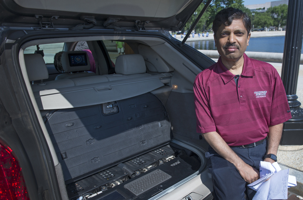 Carnegie Mellon University Professor Raj Rajkumar, shown in 2014 with the main control center of a self-driven car, said he is more convinced than ever that gradually introducing safe-driving features such as lane-departure warnings, cameras and sensors is the prudent path.
At left, Google's self-driving Lexus motors  along a street during a demonstration at Google campus in Mountain View, Calif.
