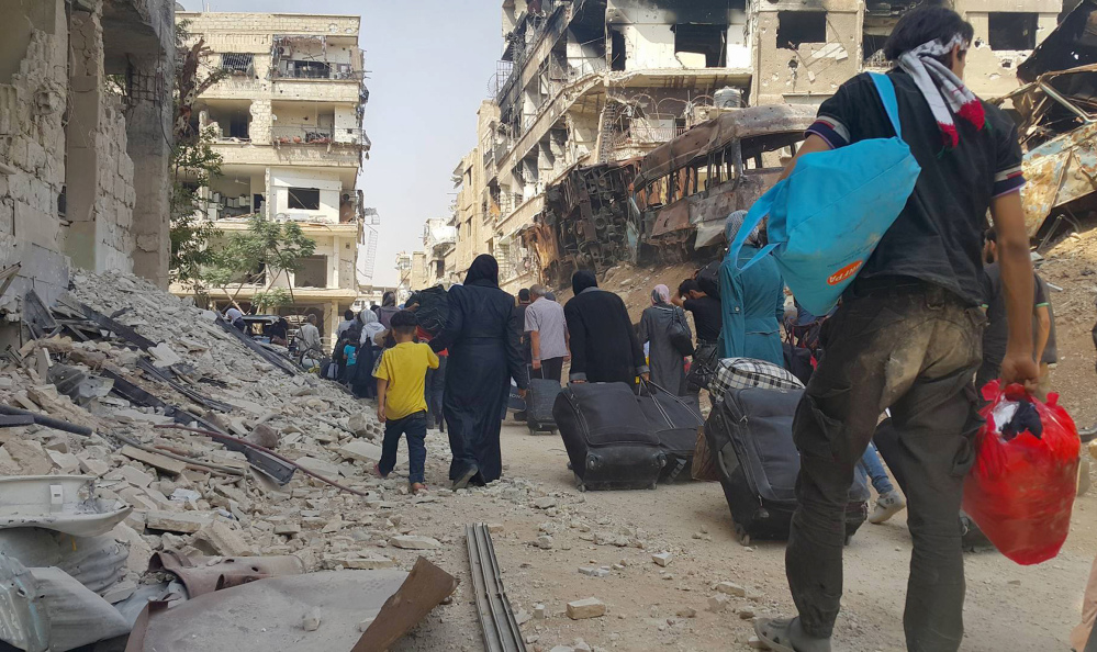 Syrian citizens carry their belongings as they prepare to evacuate from Darayya, a blockaded Damascus suburb, on Friday under a deal struck between the rebels and the government.