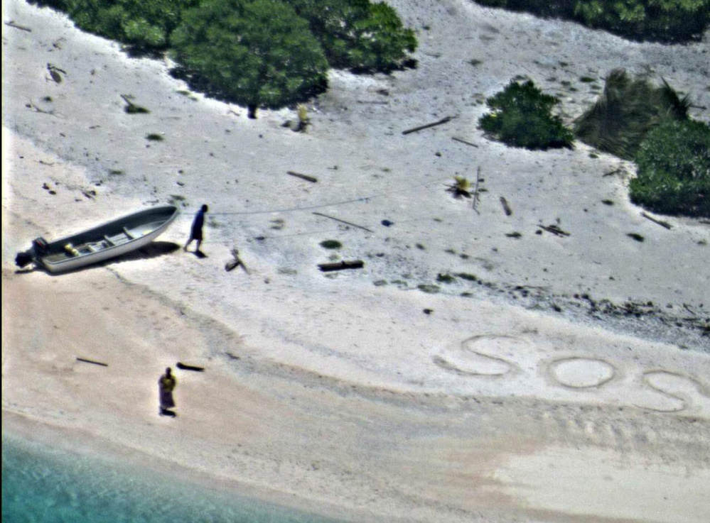 Two stranded mariners signal for help with an "SOS" in the sand as a Navy P-8A Poseidon aircraft crew flies over as part of a Coast Guard search of the Pacific on Wednesday.