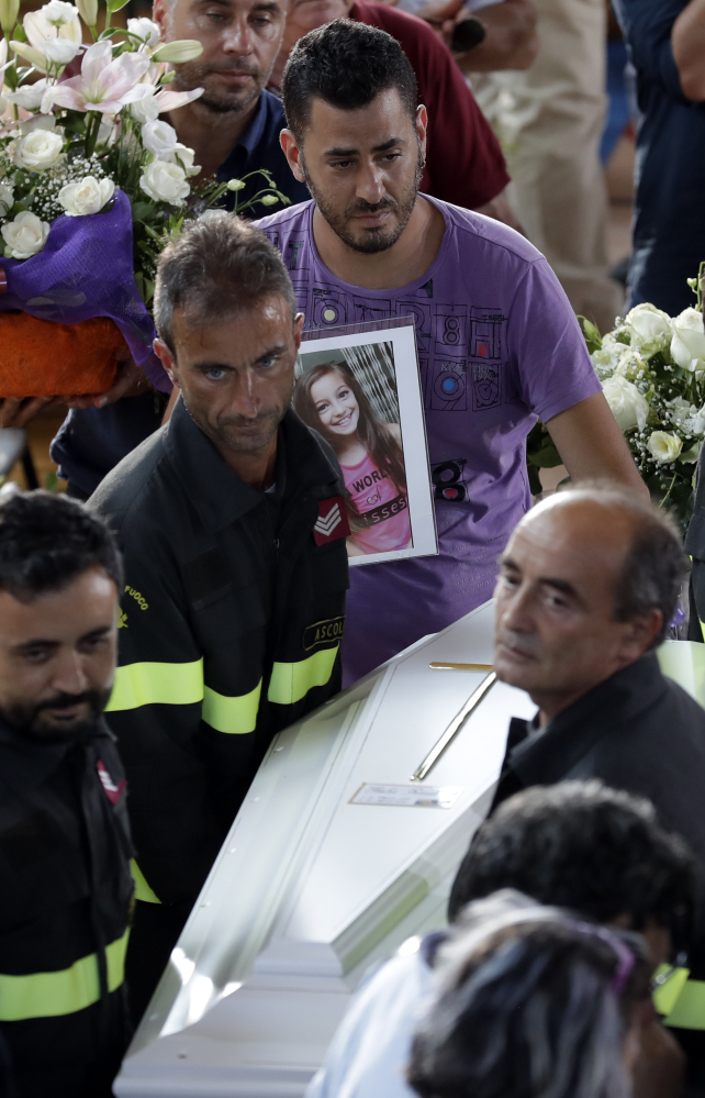 The coffin of 9-year-old Giulia Rinaldo is carried outside a gymnasium at the end of the state funeral service for earthquake victims in Ascoli Piceno, Italy, on Saturday. Giulia's body was found sprawled over her younger sister, who survived, possibly because her sister protected her.