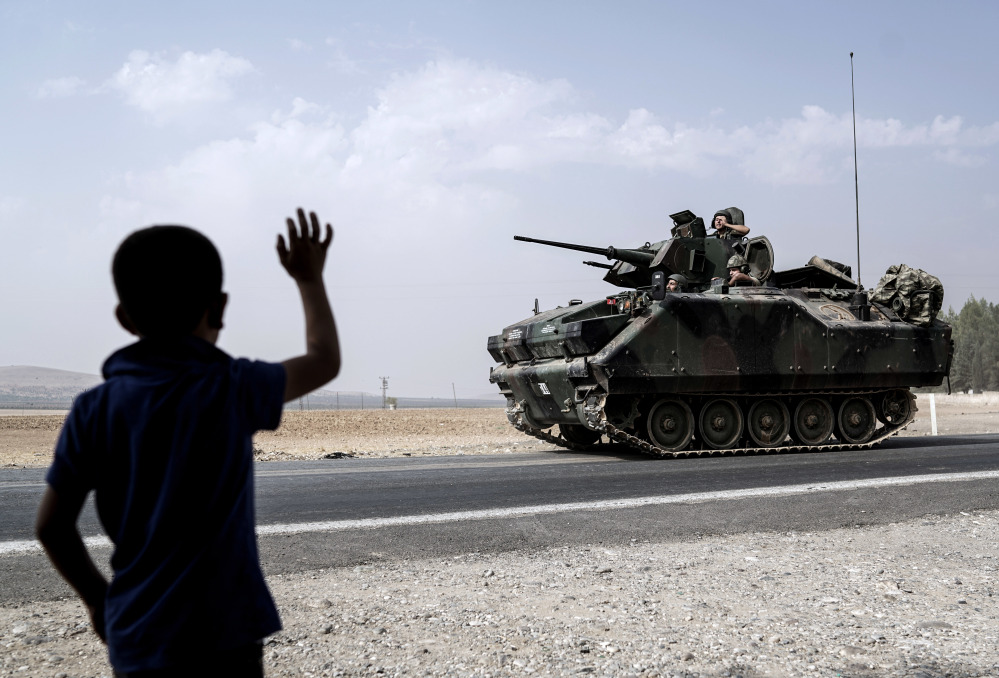 A child waves at Turkish troops heading to the Syrian border, in Karkamis, Turkey, on Friday. Turkish tanks led the assault last week that recaptured Jarabulus, Syria, from Islamic State militants in a relatively bloodless victory.