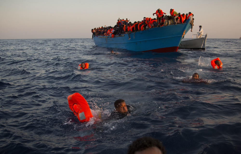Migrants swim from a crowded boat to reach help during a rescue operation Monday in the Mediterranean Sea near Libya. Five-day-old premature twins were among those picked up by a Doctors Without Borders vessel.