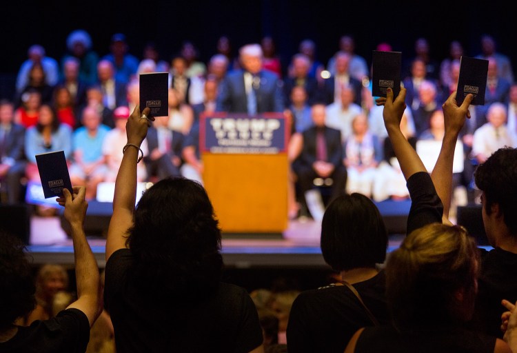Protesters hold up pocket Constitutions during Thursday's rally by Donald Trump's campaign at Merrill Auditorium.